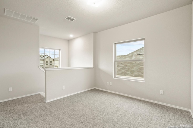 carpeted empty room with a textured ceiling