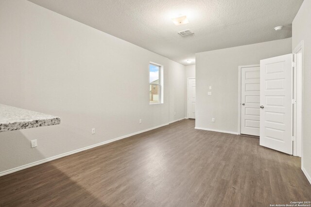 unfurnished bedroom featuring a textured ceiling and dark wood-type flooring