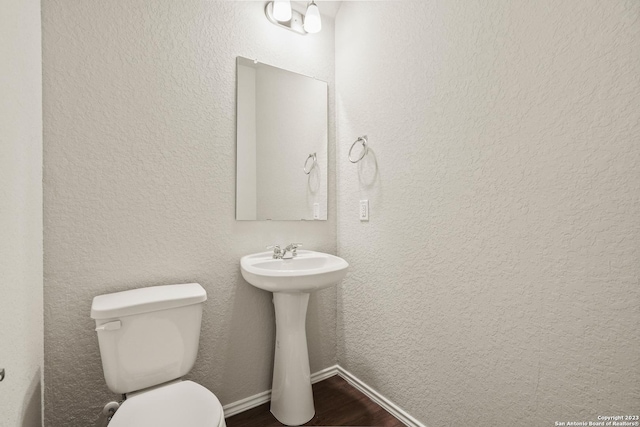 bathroom featuring wood-type flooring, toilet, and sink