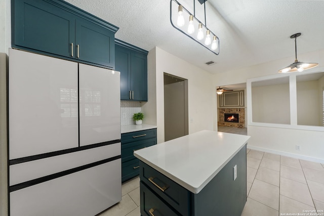 kitchen with a kitchen island, white refrigerator, a fireplace, tasteful backsplash, and ceiling fan