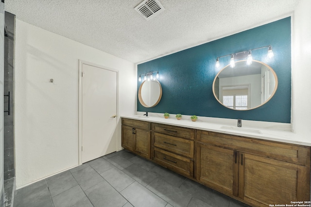 bathroom with a textured ceiling, tile patterned floors, and vanity