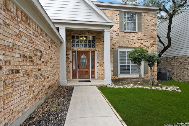 entrance to property featuring a lawn and central air condition unit