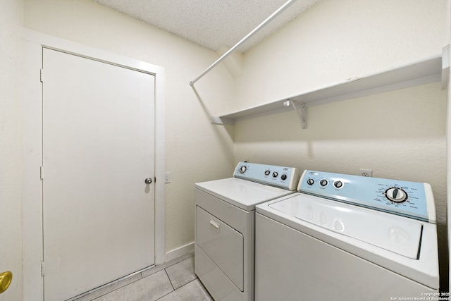 laundry room featuring light tile patterned flooring, washing machine and clothes dryer, and a textured ceiling