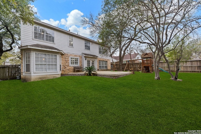 rear view of property featuring a playground, a patio area, and a yard