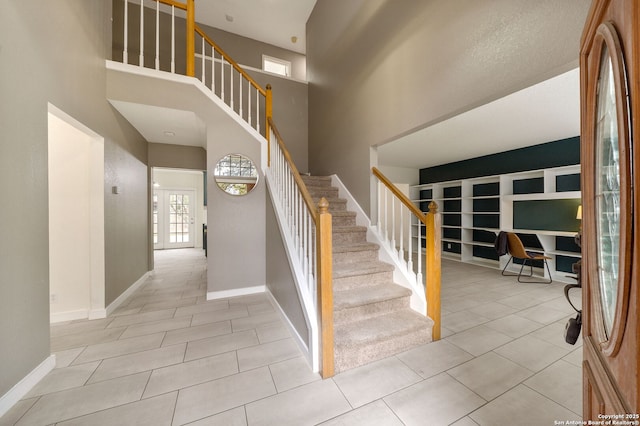 stairway featuring tile patterned floors and a high ceiling