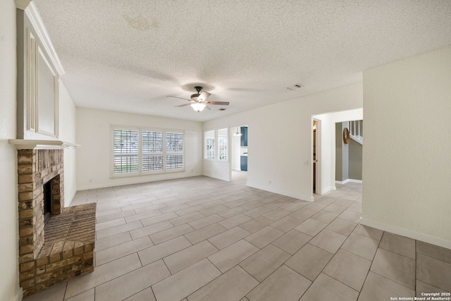 unfurnished living room featuring ceiling fan, a fireplace, light tile patterned flooring, and a textured ceiling