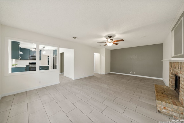 unfurnished living room with ceiling fan, sink, a textured ceiling, and a fireplace