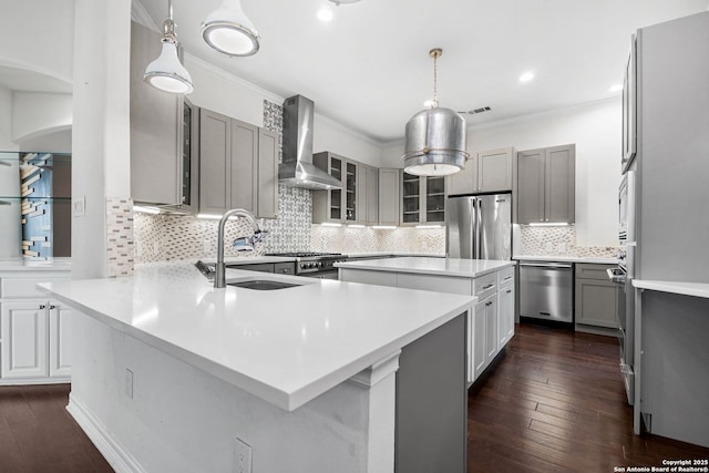 kitchen with gray cabinetry, sink, a center island, wall chimney range hood, and appliances with stainless steel finishes