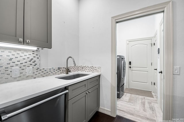 laundry area with washer / clothes dryer, sink, and dark wood-type flooring