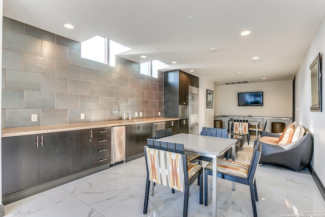 kitchen featuring sink, decorative backsplash, and dark brown cabinets