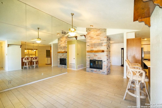 unfurnished living room featuring a brick fireplace, lofted ceiling, and ceiling fan