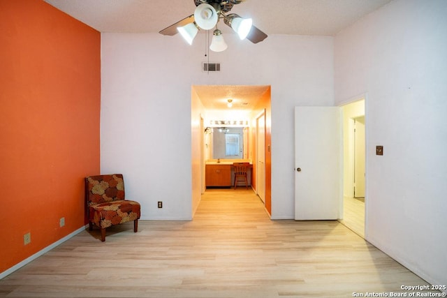 interior space featuring ceiling fan, light hardwood / wood-style floors, and a high ceiling