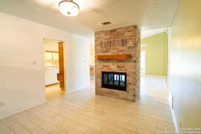 unfurnished living room with vaulted ceiling, a multi sided fireplace, a textured ceiling, and light hardwood / wood-style flooring