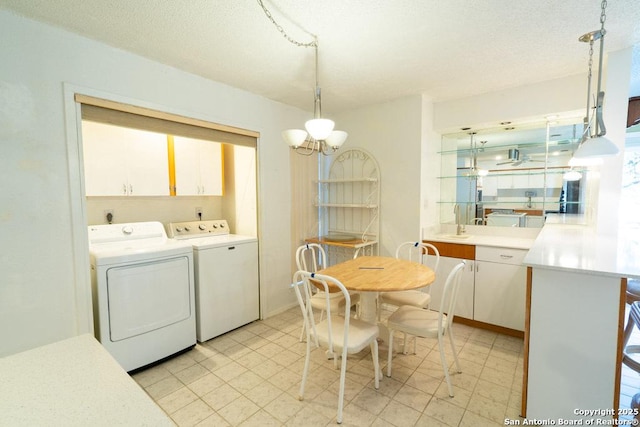 laundry area featuring a healthy amount of sunlight, a notable chandelier, washing machine and clothes dryer, and cabinets