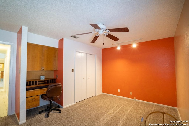 home office with a textured ceiling, ceiling fan, track lighting, and carpet