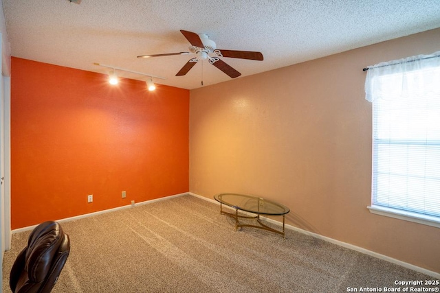 unfurnished room with ceiling fan, rail lighting, a textured ceiling, and carpet