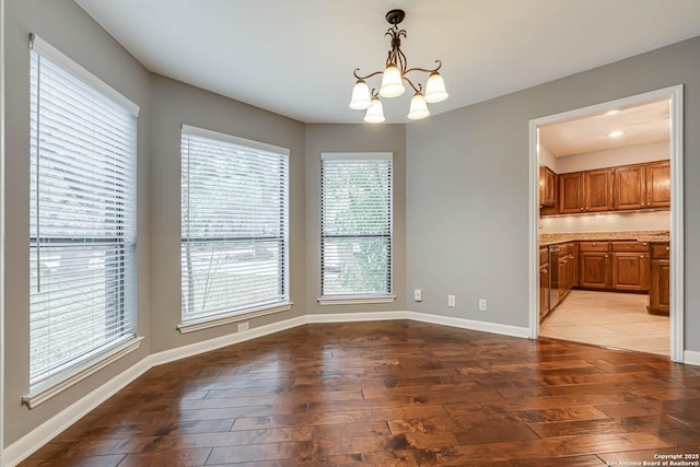 unfurnished dining area with plenty of natural light, a chandelier, and hardwood / wood-style flooring