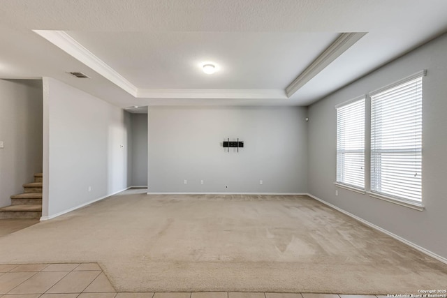 carpeted empty room with a tray ceiling and crown molding