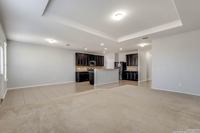 unfurnished living room featuring a tray ceiling, ornamental molding, and light tile patterned flooring