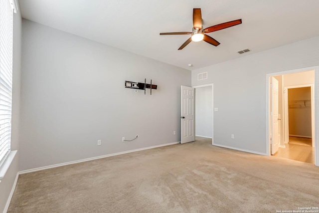 unfurnished bedroom featuring ceiling fan, light colored carpet, a spacious closet, and a closet