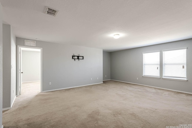 empty room with a textured ceiling and light colored carpet