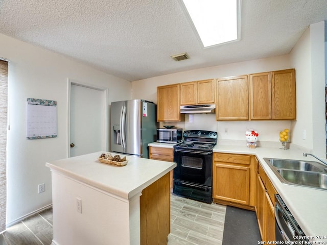 kitchen with black appliances, a kitchen island, sink, and a textured ceiling