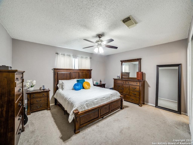 carpeted bedroom with ceiling fan and a textured ceiling