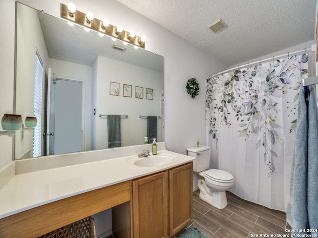 bathroom with vanity, a textured ceiling, toilet, and walk in shower