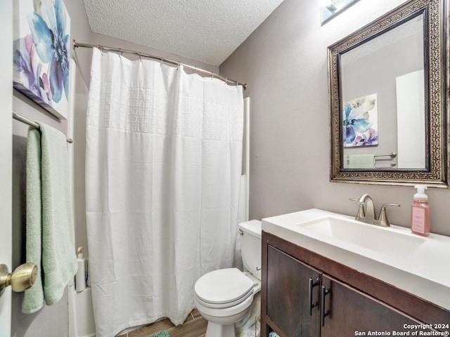 bathroom with vanity, toilet, and a textured ceiling