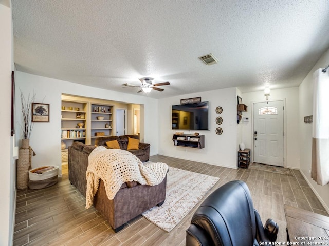 living room with a textured ceiling and ceiling fan