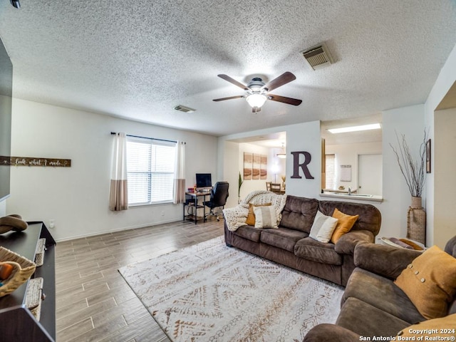 living room featuring ceiling fan and a textured ceiling