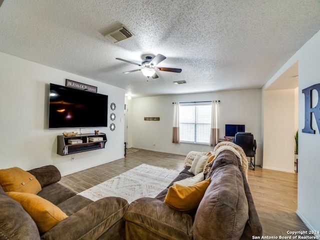 living room featuring hardwood / wood-style floors, ceiling fan, and a textured ceiling