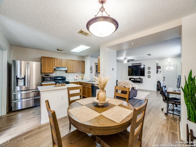 dining area featuring ceiling fan, sink, and a textured ceiling