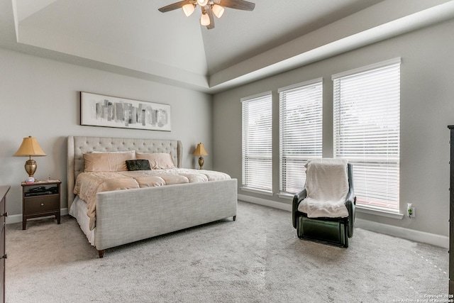 carpeted bedroom featuring multiple windows, a tray ceiling, ceiling fan, and lofted ceiling