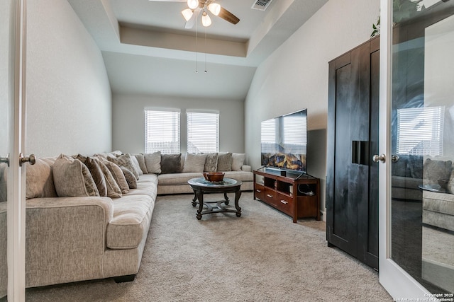 living room with a raised ceiling, light carpet, and ceiling fan