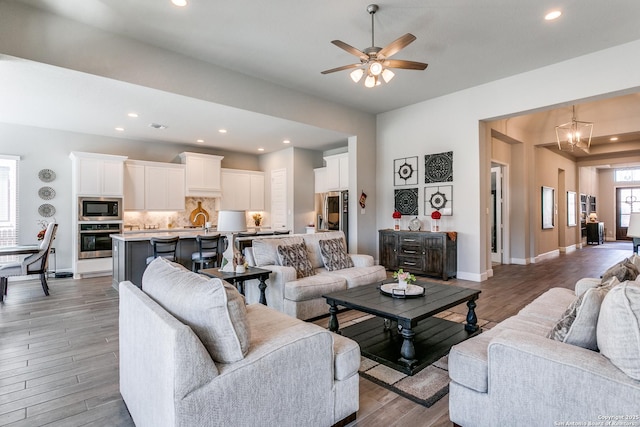 living room featuring sink, ceiling fan with notable chandelier, and light wood-type flooring