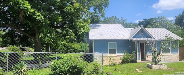 view of front facade with a standing seam roof, stone siding, and a fenced front yard