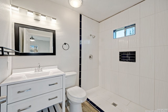 bathroom with vanity, toilet, and tiled shower