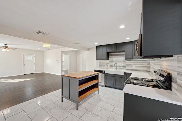 kitchen featuring gray cabinetry, ceiling fan, sink, backsplash, and appliances with stainless steel finishes