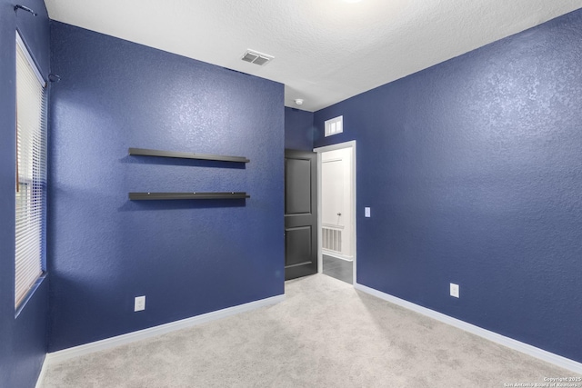 carpeted spare room featuring a textured ceiling