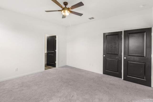 unfurnished bedroom featuring ceiling fan, light colored carpet, and connected bathroom