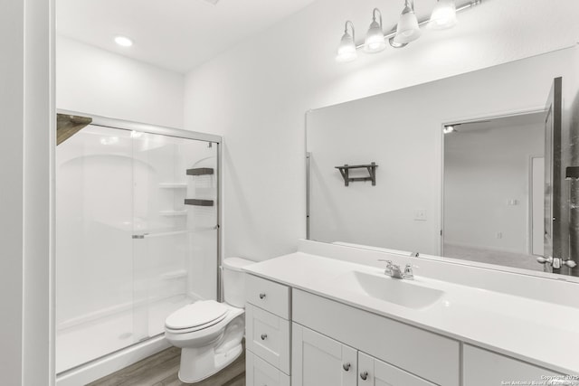 bathroom featuring wood-type flooring, vanity, toilet, and walk in shower