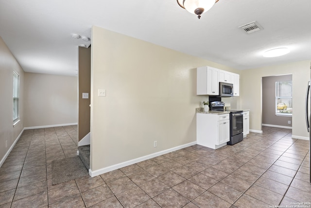 kitchen featuring white cabinetry, light tile patterned floors, and black / electric stove