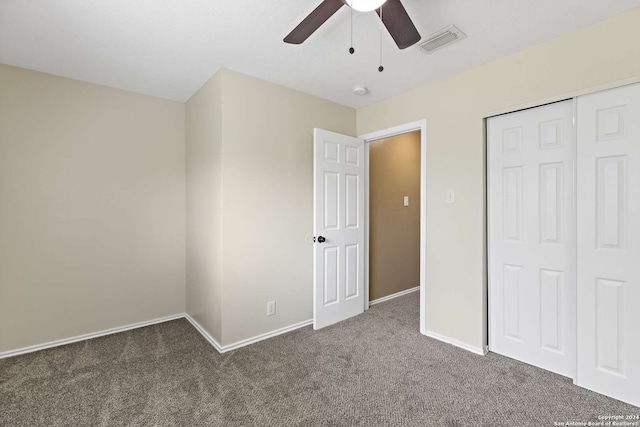 unfurnished bedroom featuring dark colored carpet, a closet, and ceiling fan