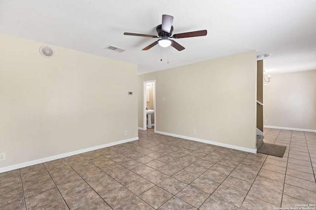 tiled empty room with ceiling fan with notable chandelier