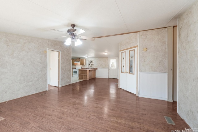 unfurnished living room with ceiling fan and dark wood-type flooring