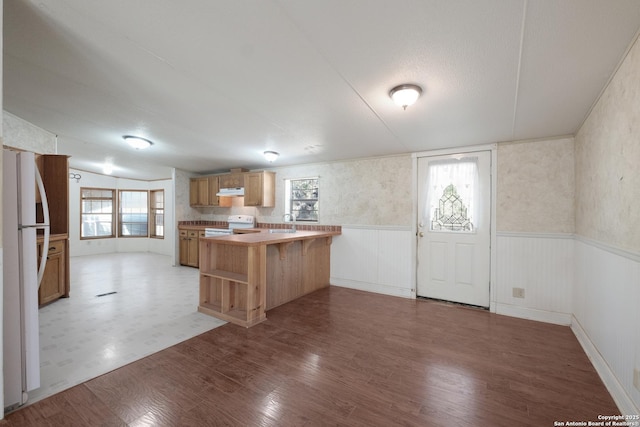 kitchen with kitchen peninsula, a kitchen breakfast bar, white appliances, and plenty of natural light