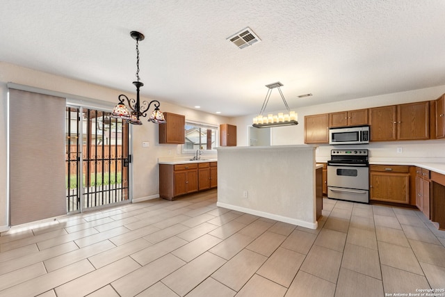 kitchen with pendant lighting, sink, a kitchen island, stainless steel appliances, and a chandelier