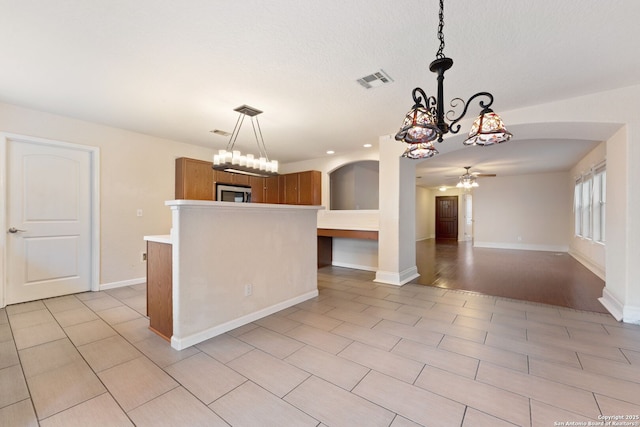 kitchen featuring pendant lighting, ceiling fan with notable chandelier, a center island, and light tile patterned floors