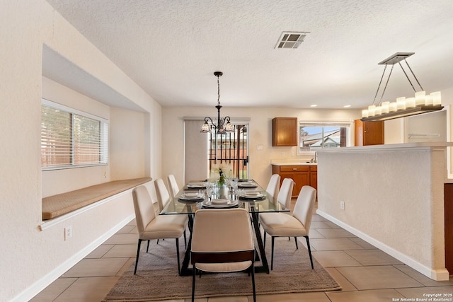 tiled dining area featuring a textured ceiling and a notable chandelier